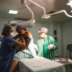 A doctor, nurse , and medical student assisting a patient in an operating theatre