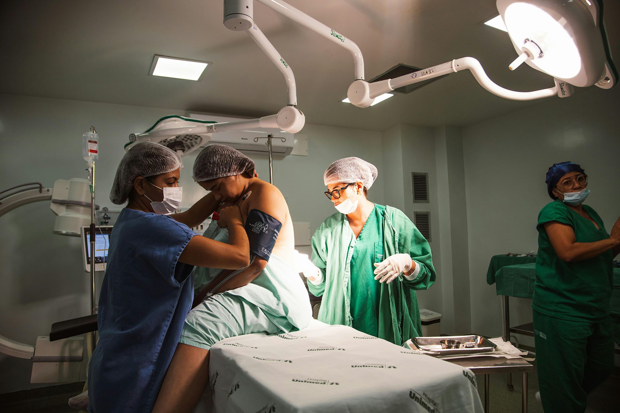 A doctor, nurse , and medical student assisting a patient in an operating theatre